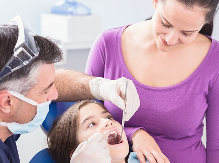 pediatric-dentist-examining-young-patient-with-her-mother 1